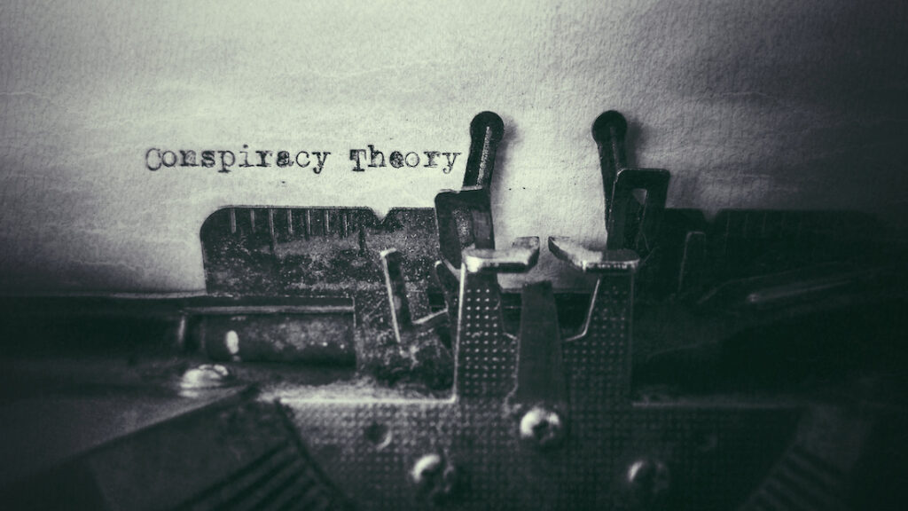 Image of a typewriter typing the words "conspiracy theory" on a piece of paper.
